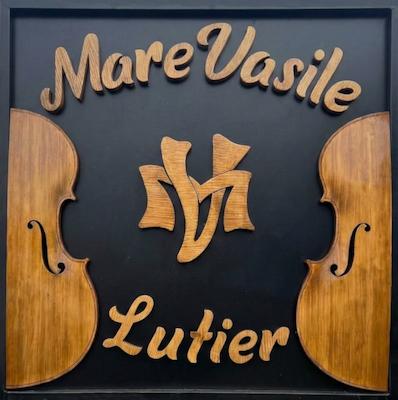 Sigla sculptată a atelierului Mare Vasile — două jumătăți de vioară și monograma MV